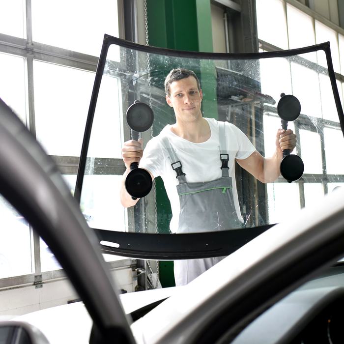Autoglaser hebt eine neue Scheibe mit Saugnäpfen an